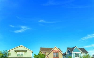 Low angle view of three colorful ahouses with traditional designs at Daybreak, Utah. Exterior of the second floor part of the two-storey houses with trees at the front against the vivid blue sky.